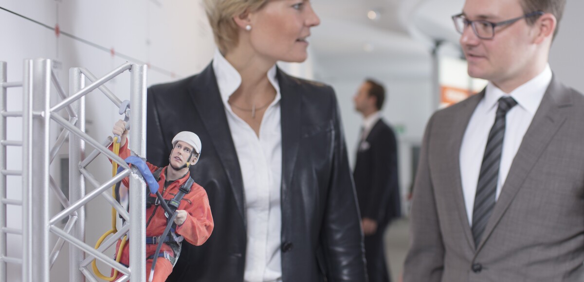 Zwei Personen, eine Frau und ein Mann, im Gespräch vor einer 3D-Miniatur des Evers-PSA-Kletterturms